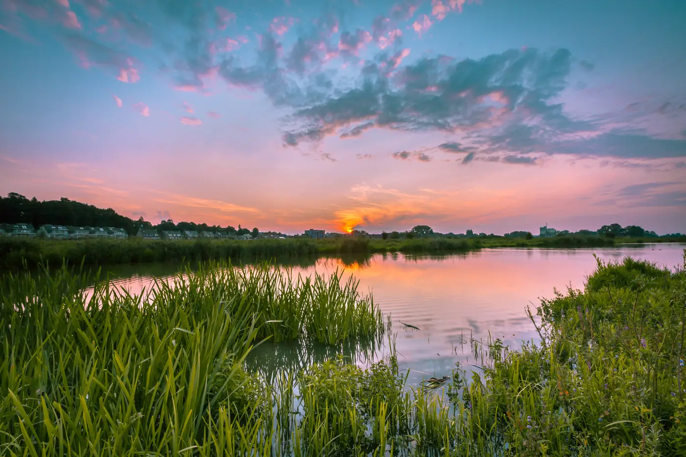 Sonnenuntergang über einer ruhigen Flusslandschaft mit Schilf