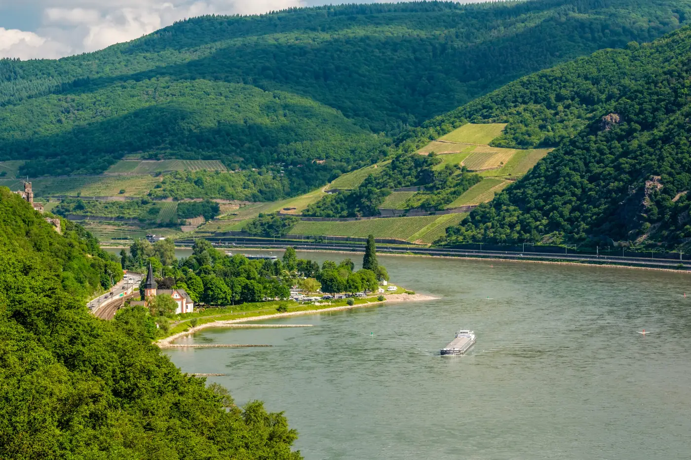 Der Rhein im Rheintal mit Weinbergen und einem Frachtschiff